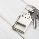 Bunch of keys with house shaped keychain on white wood